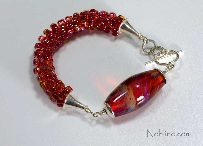Bright Pink, gold filled beads woven into a kumihimo braid on this bracelet and accented with an oval bright pink handmade lampwork bead with silver caps, and cones. jump rings and clasp.