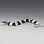 Seven flat sided lentil beads in black and white create a striking bracelet.  The ends of each bead are capped with tiny silver caps.  The clasp is a large round hammered disk with an "s" clasp .   Quite bold, would look great with a black t-shirt or a white collared shirt.